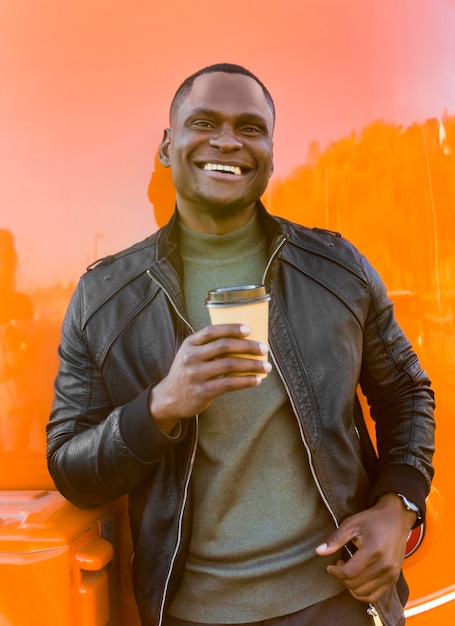 Homem de meio tiro segurando café, parado perto do food truck