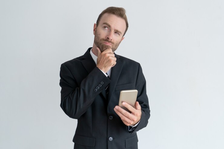 Foto grátis homem de negócio pensativo que toca no queixo, pensando e guardando o smartphone.