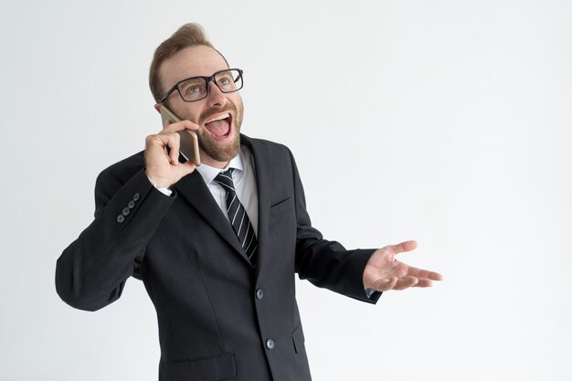 Homem de negócios animado falando no smartphone alto e gesticulando.