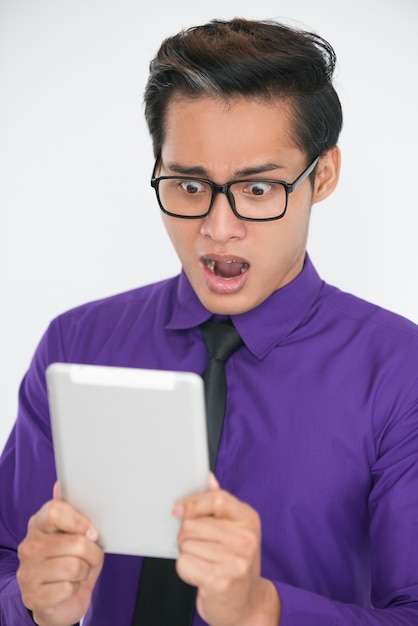 Homem de negócios asiático chocado usando a Tablet