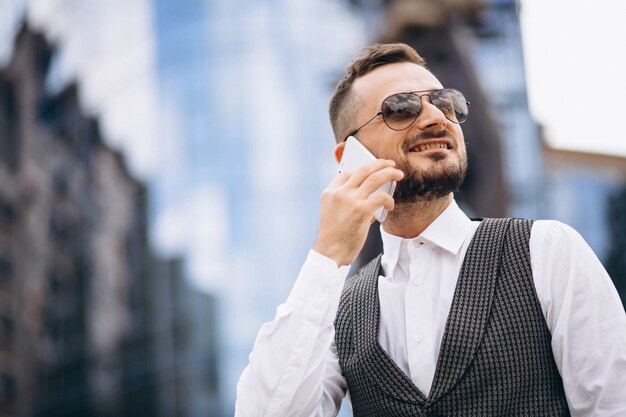 Homem de negócios bem sucedido pelo arranha-céu, falando ao telefone