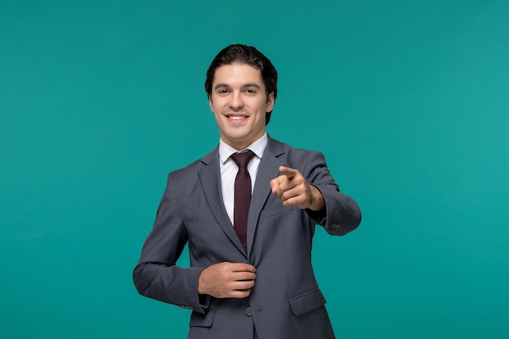 Foto grátis homem de negócios, bonitão, bonito, terno de escritório cinza, sorrindo e apontando para a frente