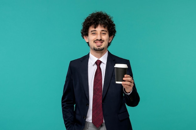 Homem de negócios bonitinho cara bonito com roupa de escritório preto sorrindo e segurando o copo de papel