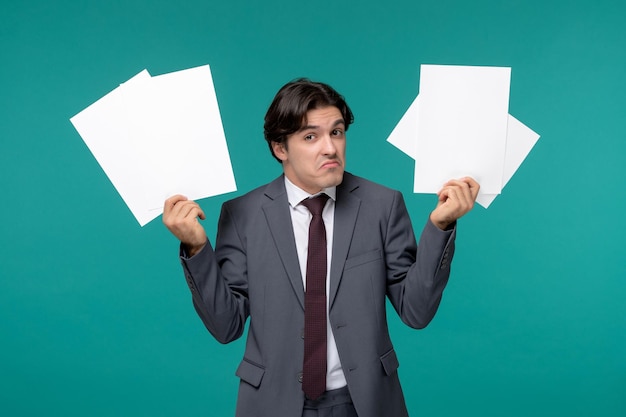 Homem de negócios bonito bonitão de terno cinza e gravata confuso segurando folhas de papel