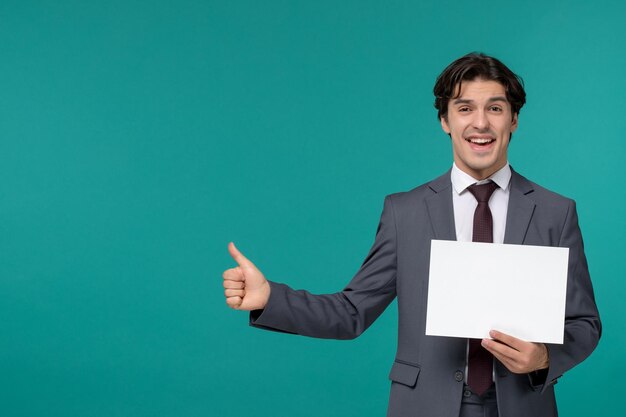 Homem de negócios bonito bonitão de terno cinza e gravata sorrindo e segurando um papel