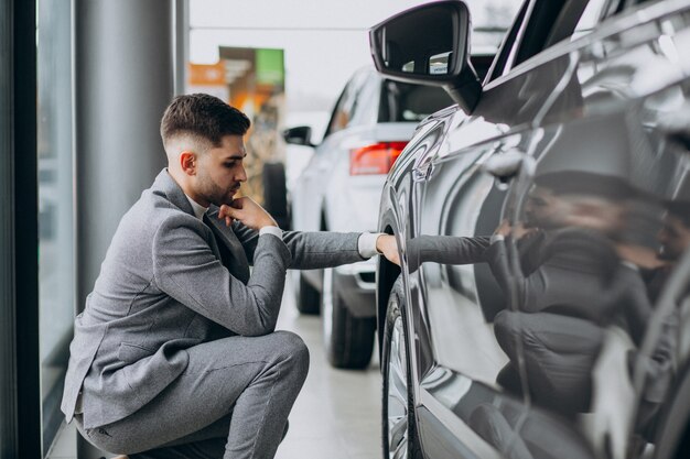 Homem de negócios bonito escolhendo um carro em uma sala de exposições