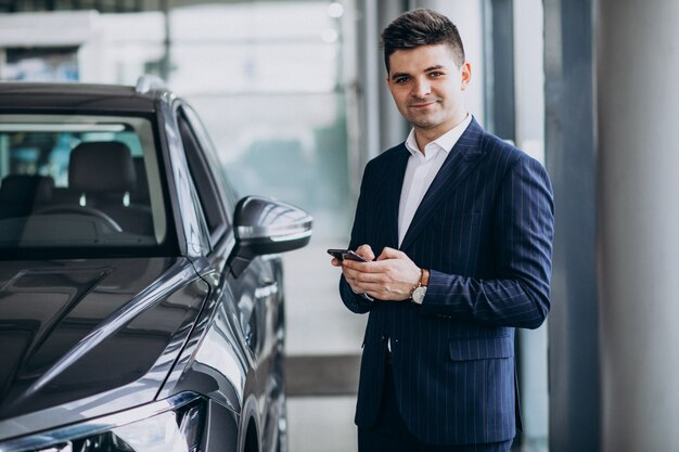 Homem de negócios bonito jovem em uma sala de exposições de carro, escolhendo um carro