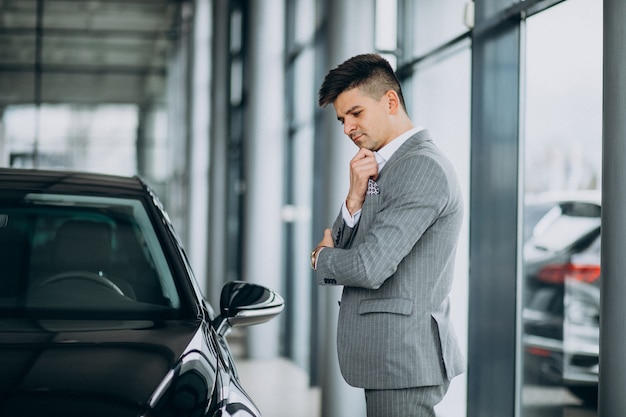 Homem de negócios bonito jovem escolhendo um carro em uma sala de exposições de carros