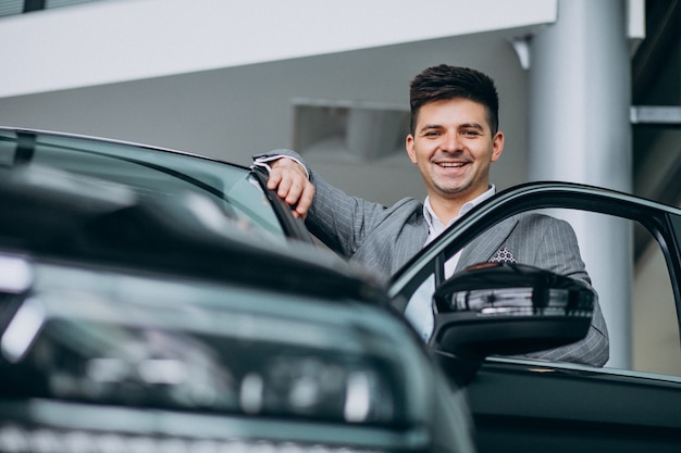 Homem de negócios bonito jovem escolhendo um carro em uma sala de exposições de carros