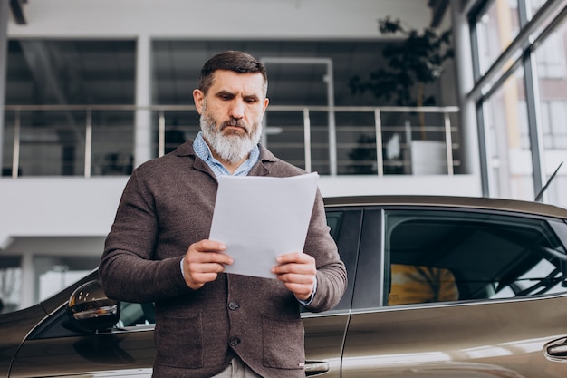 Foto grátis homem de negócios bonito lendo documentos sobre aluguel de carros