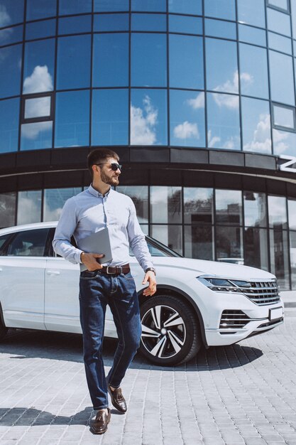 Homem de negócios bonito pelo carro branco