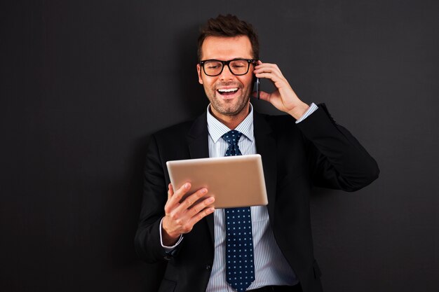 Homem de negócios bonito trabalhando com celular e tablet digital