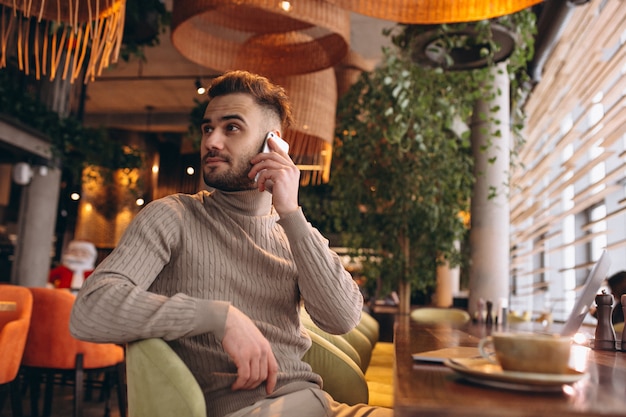 Homem de negócios bonito trabalhando no computador e tomando café em um café