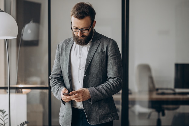 Homem de negócios bonito usando o telefone no escritório