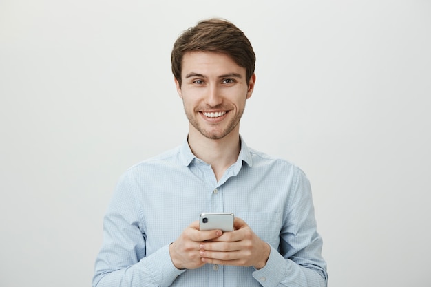 Homem de negócios bonito usando telefone celular, sorrindo