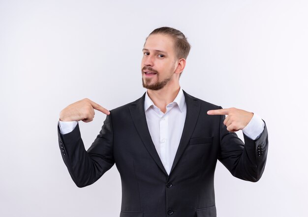 Homem de negócios bonito vestindo terno apontando com o dedo indicador para si mesmo, em pé sobre um fundo branco