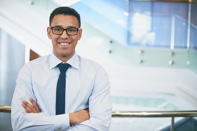 Homem de negócios com vidros e os braços dobrados