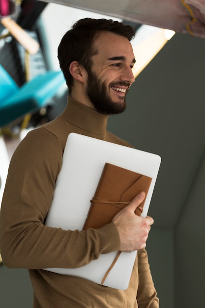 Homem de negócios de vista lateral com laptop e agenda