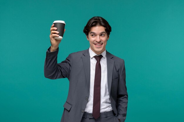 Homem de negócios elegante bonito homem bonito de terno cinza e gravata sorrindo e segurando a xícara de café