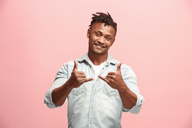 Homem de negócios feliz em pé e sorrindo contra rosa