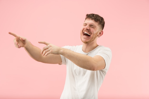 Homem de negócios feliz em pé e sorrindo isolado no fundo rosa do estúdio. Belo retrato masculino com metade do corpo. Jovem emocional.