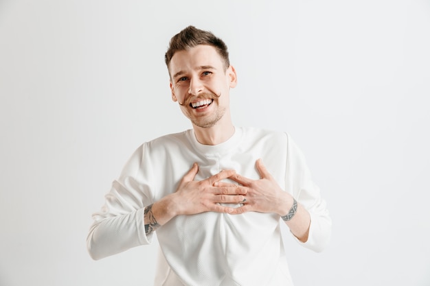 Homem de negócios feliz em pé, sorrindo isolado no espaço cinza. Belo retrato masculino com metade do corpo. Jovem satisfazer homem