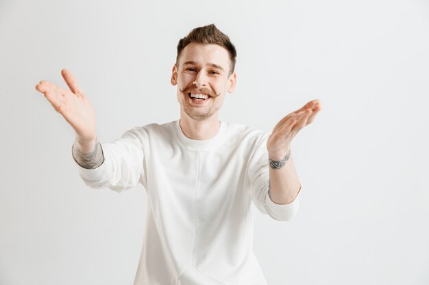 Homem de negócios feliz em pé, sorrindo isolado no fundo cinza do estúdio. Belo retrato masculino com metade do corpo. Jovem satisfazer o homem. Emoções humanas, conceito de expressão facial.