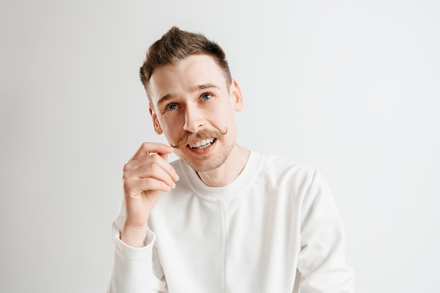 Homem de negócios feliz em pé, sorrindo, isolado no fundo cinza do estúdio. belo retrato masculino com metade do corpo. jovem satisfazer o homem. emoções humanas, conceito de expressão facial.