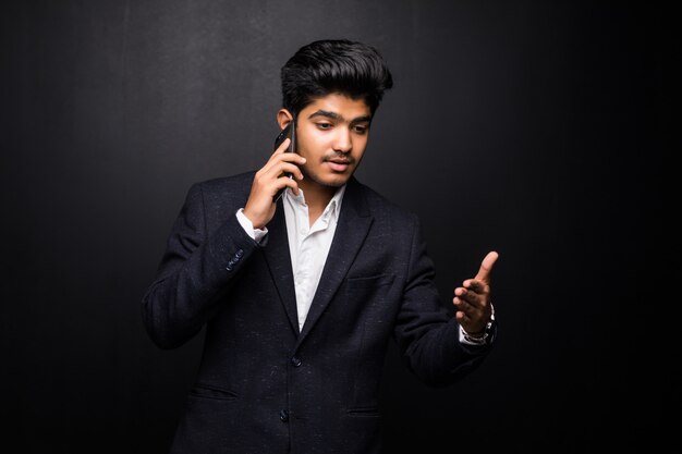 Homem de negócios indiano falando no telefone na parede preta