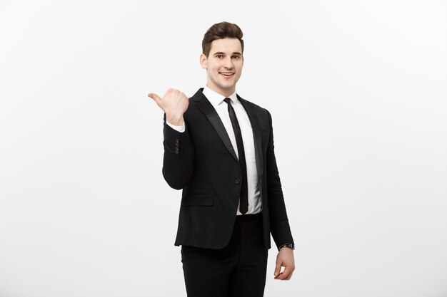 Homem de negócios jovem bonito sorriso feliz apontar o dedo para o espaço vazio da cópia, empresário mostrando o lado apontando, conceito de produto de propaganda, isolado sobre fundo branco.