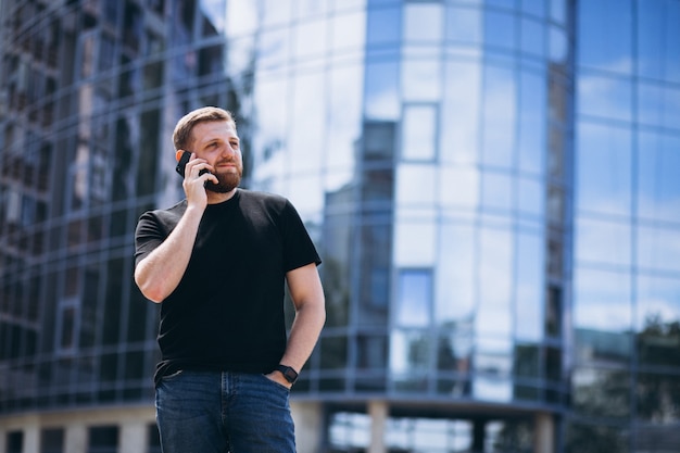 Homem de negócios jovem falando no telefone pelo arranha-céu