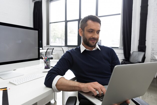 Homem de negócios jovem sorridente usando laptop