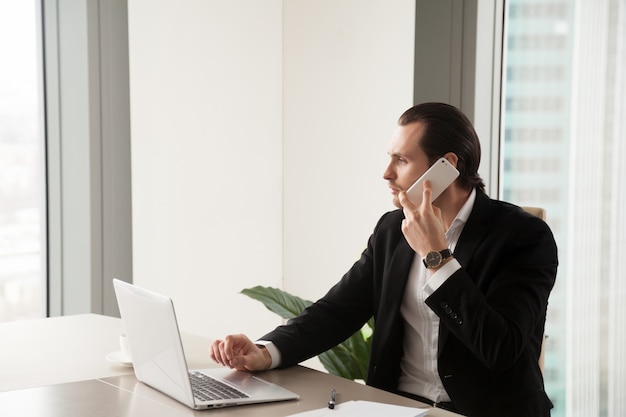 Homem de negócios novo sério no escritório que faz o telefonema.