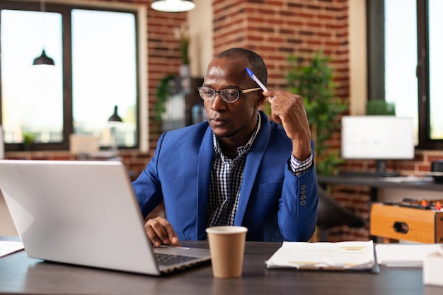 Homem de negócios, pensando em solução inovadora e planejamento de projeto no laptop. Empreendedor pensativo, debatendo ideias financeiras para planejar a estratégia de marketing no computador para inicialização.