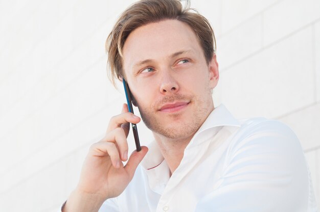 Homem de negócios pensativo chamando no smartphone ao ar livre
