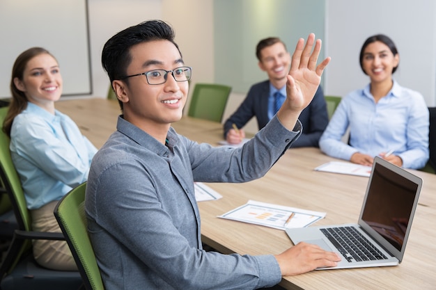 Homem de negócios que levanta a mão na conferência sorrindo