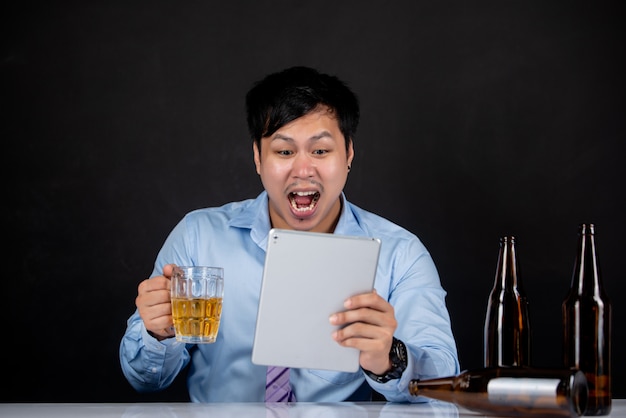 Homem de negócios, segurando um laptop com uma caneca de cerveja