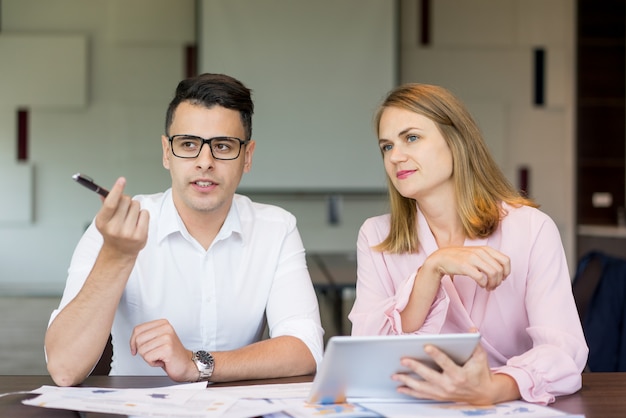 Homem de negócios seguro que fala ao colega fêmea na instrução.