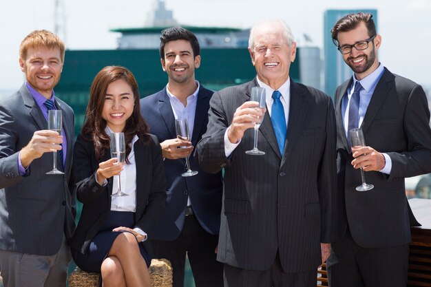 Homem de negócios sênior com mais pessoas de negócios com taças de champanhe