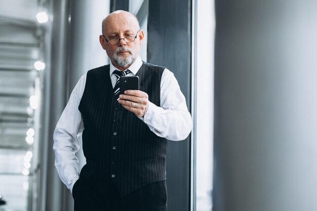 Homem de negócios sênior falando ao telefone no escritório