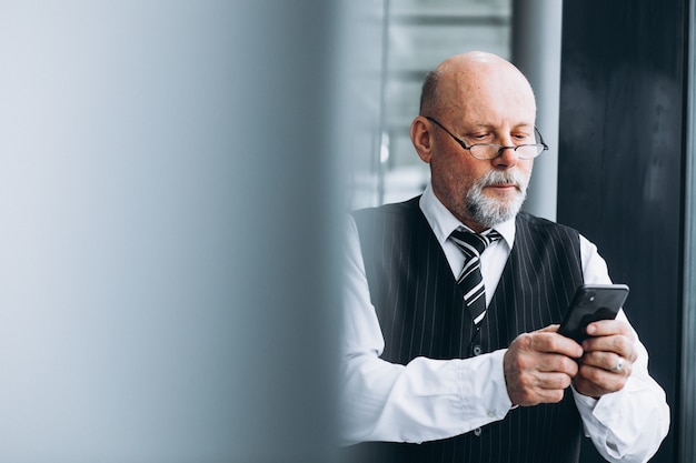 Homem de negócios sênior falando ao telefone no escritório