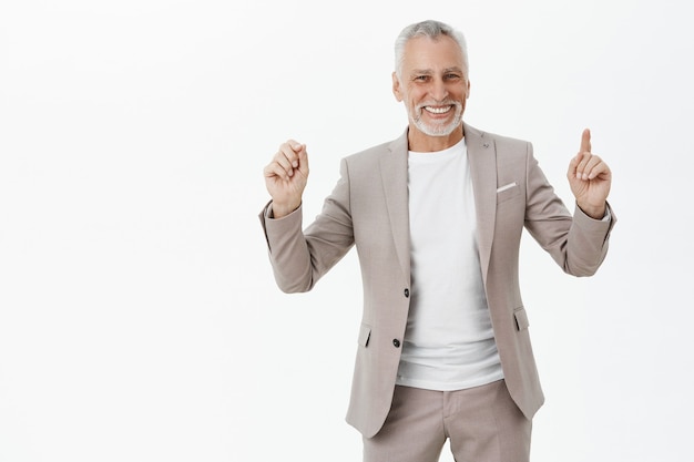 Foto grátis homem de negócios sênior sorridente e alegre apontando os dedos para cima