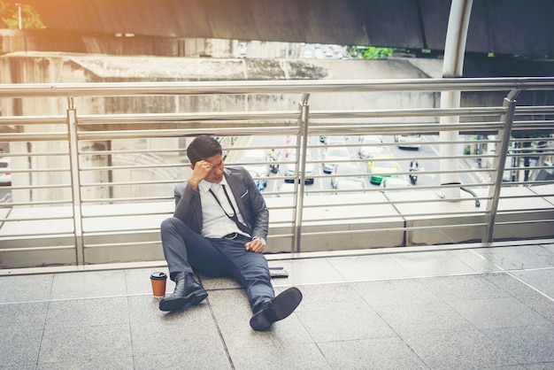 Homem de negócios sentado no chão estressado.