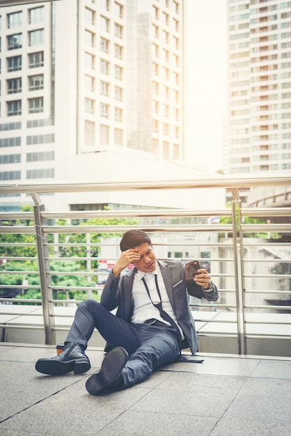 Foto grátis homem de negócios sentado no chão estressado.