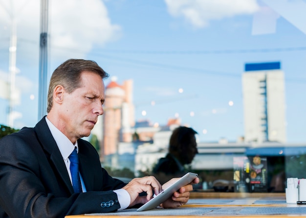 Homem de negócios sério usando tablet digital no restaurante