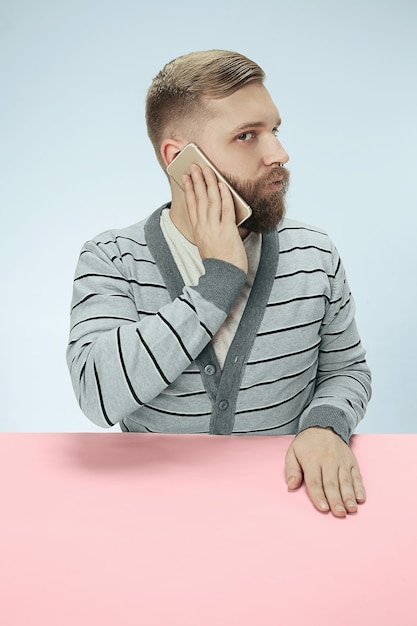 Homem de negócios surpreso, falando no telefone, sentado à mesa.