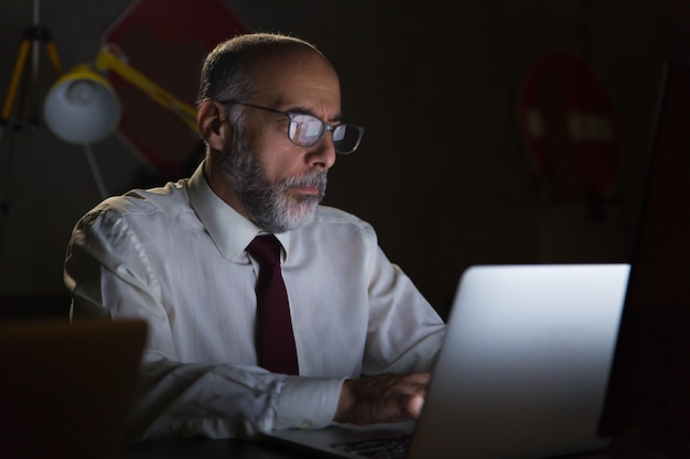 Homem de negócios usando laptop no escritório escuro