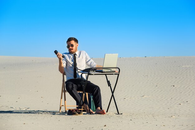 Homem de negócios usando o laptop no deserto