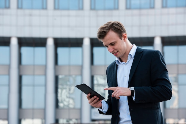 Homem de negócios usando tablet perto de prédio