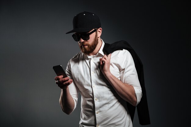 Homem de óculos escuros e camisa, segurando o telefone e desviar o olhar